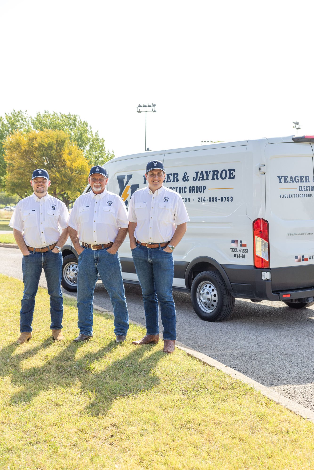 Three YJ electricians in company shirts standing in front of the YJ van